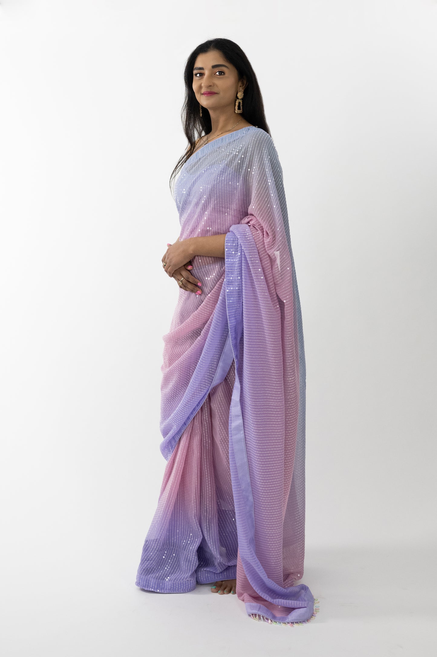 A full view of the “Sequin Dreams Georgette Saree” in a soft lavender hue, adorned with sequin details. The saree’s luxurious georgette fabric is light, airy, and beautifully draping, providing a comfortable and flattering fit. The serene lavender color evokes calm and elegance, perfect for creating a refined look. This ready-to-wear saree is ideal for special occasions in Australia