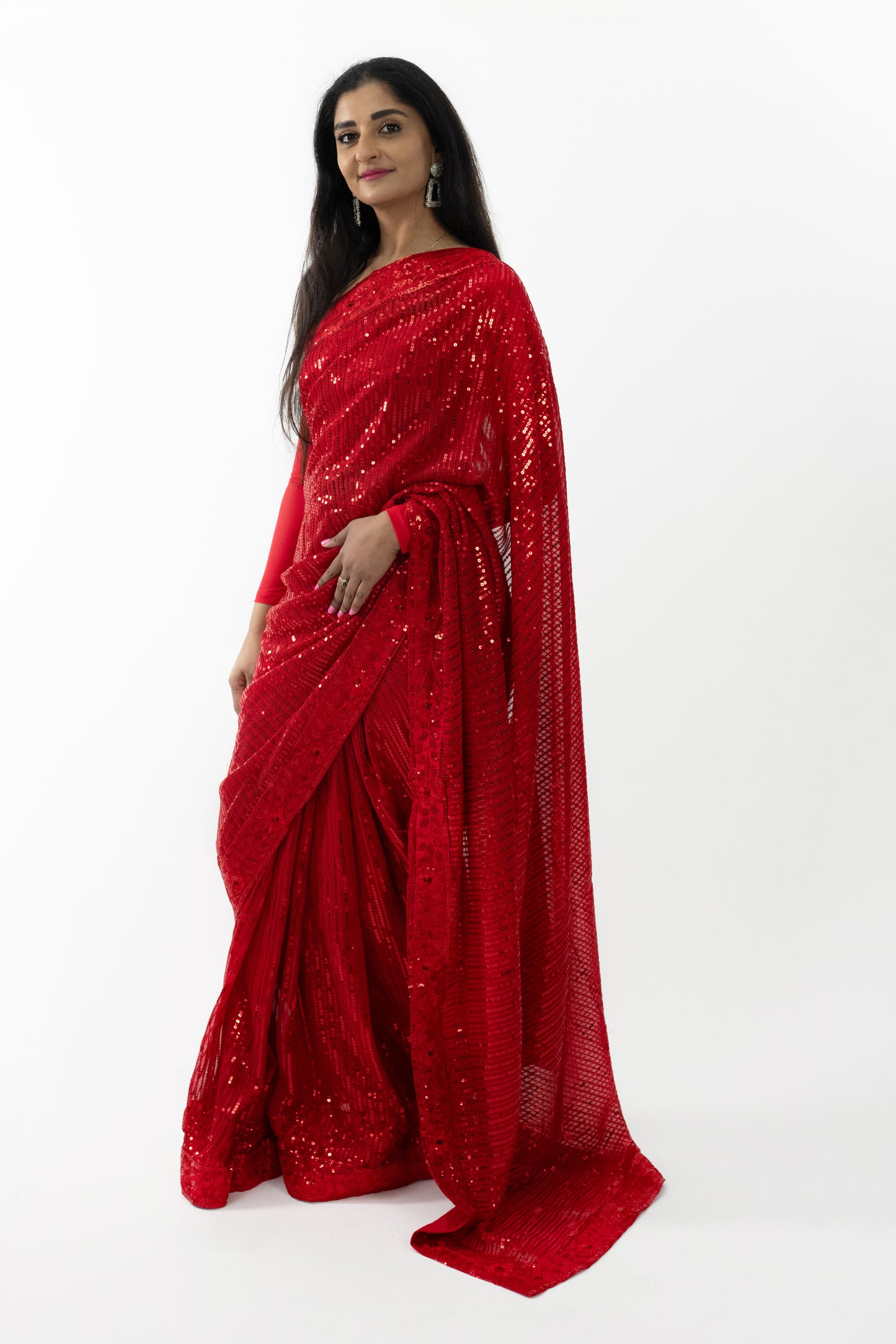 The image shows a person elegantly draped in a ready-to-wear red georgette saree in Australia. The saree features sparkling details that catch the light, showcasing meticulous craftsmanship. The soft and flowing georgette fabric provides a comfortable and flattering drape. This saree is perfect for special occasions, exuding sophistication and grace.
