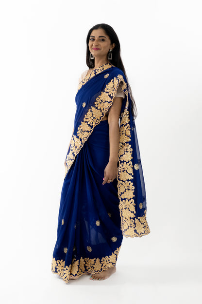 A close-up shot highlighting the exquisite gold detailing on the navy blue georgette saree. The intricate patterns showcase fine craftsmanship, adding opulence to the saree. The soft and lightweight fabric drapes beautifully, making it a stunning choice for any elegant event
