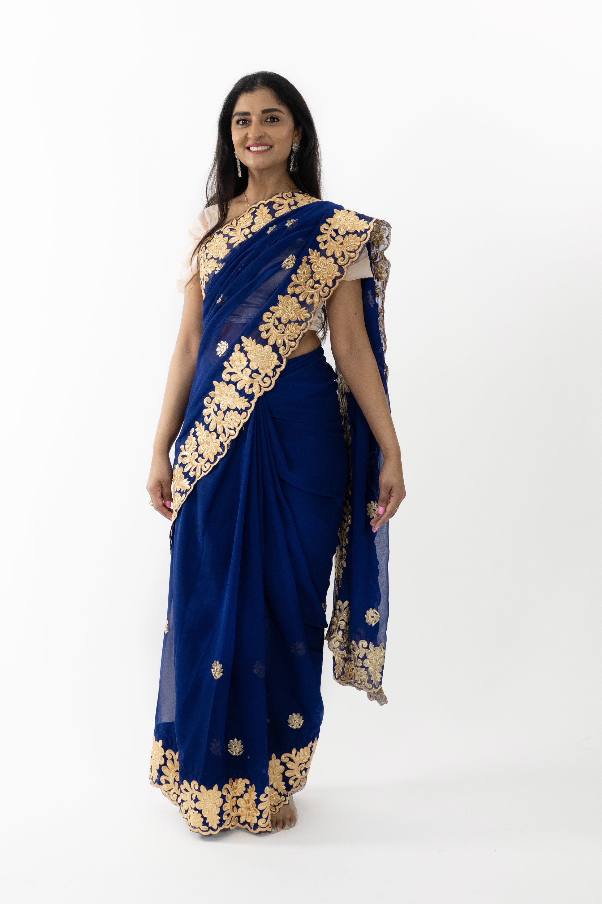  A full view of the “Midnight Enchantment Georgette Saree” in navy blue, adorned with gold patterns. The saree’s luxurious georgette fabric is soft and fluid, providing a comfortable and flattering fit. The rich navy blue hue evokes elegance and mystery, perfect for creating a refined look.