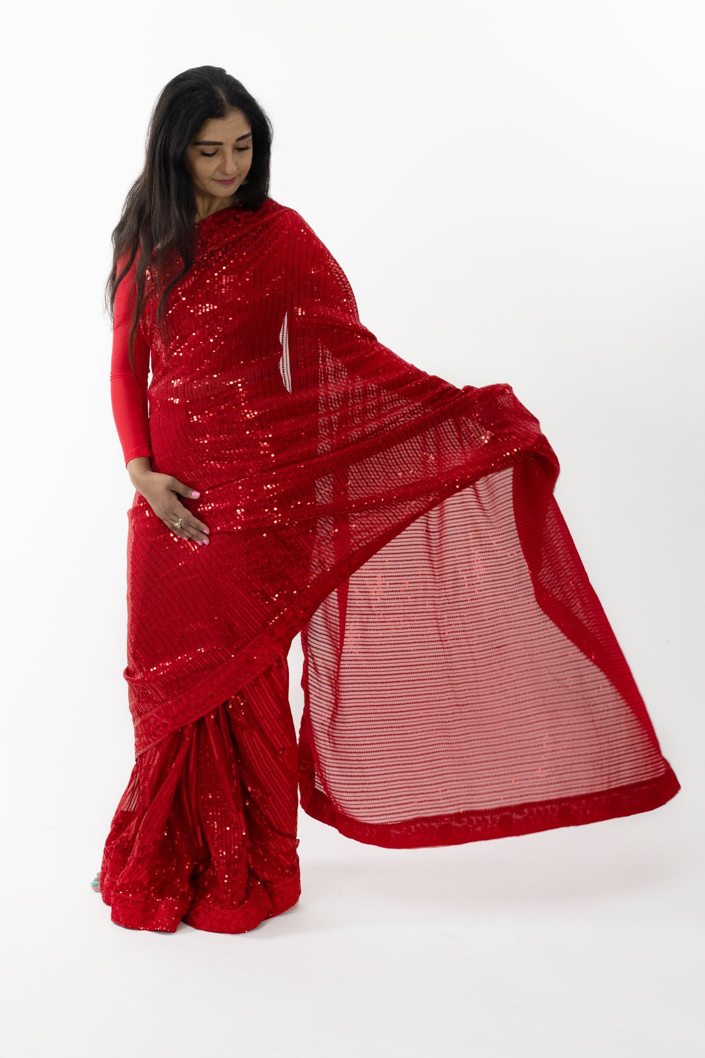 The image shows a person elegantly draped in a ready-to-wear red georgette saree in Australia. The saree features sparkling details that catch the light, showcasing meticulous craftsmanship. The soft and flowing georgette fabric provides a comfortable and flattering drape. This saree is perfect for special occasions, exuding sophistication and grace.