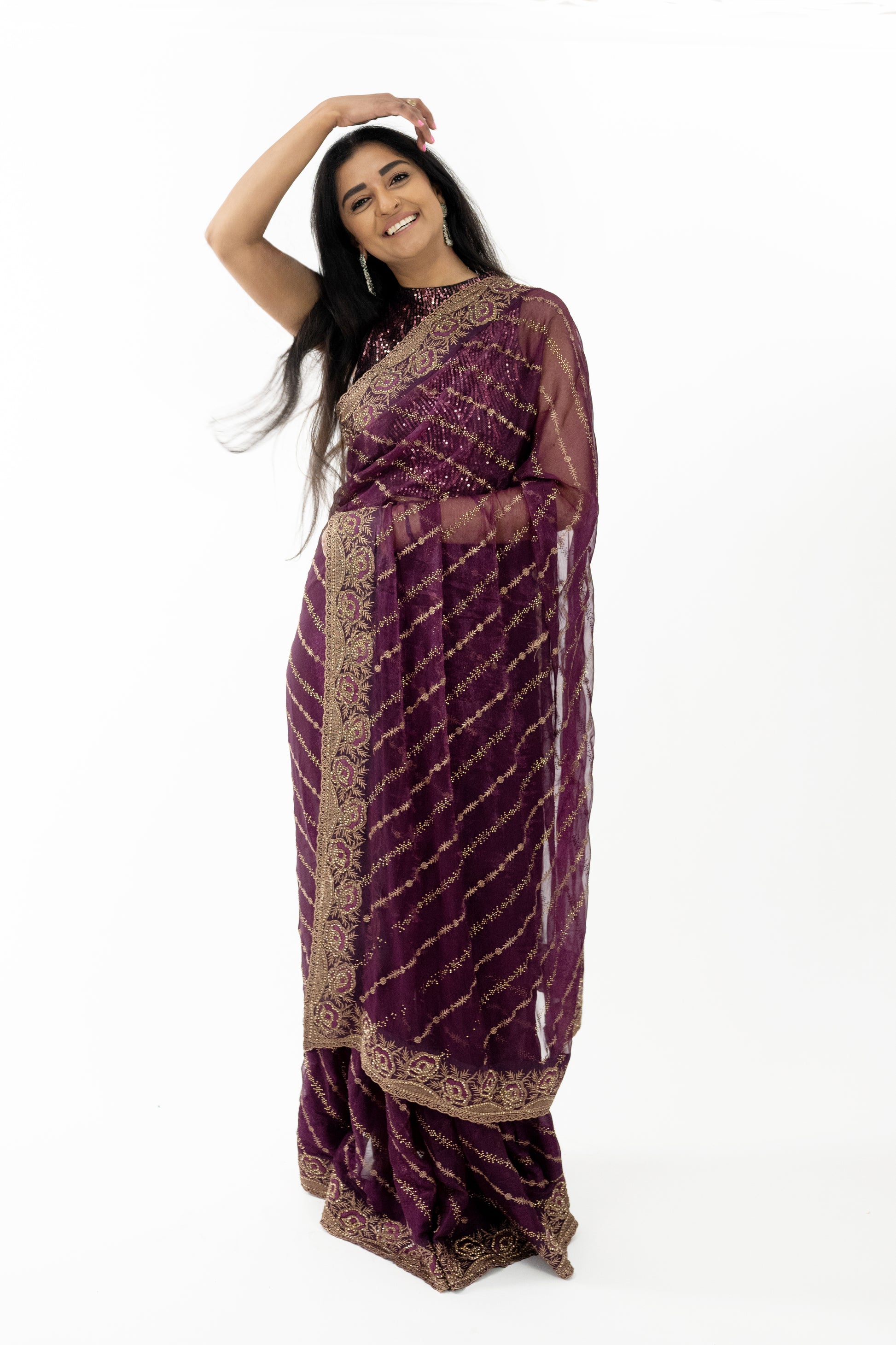 The image shows a person elegantly draped in a ready-to-wear wine Simar silk saree in Australia. The saree features intricate gold embroidery that showcases meticulous craftsmanship. The rich texture and elegant drape of the Simar silk add a touch of opulence. This saree is perfect for special occasions, exuding sophistication and grace.
