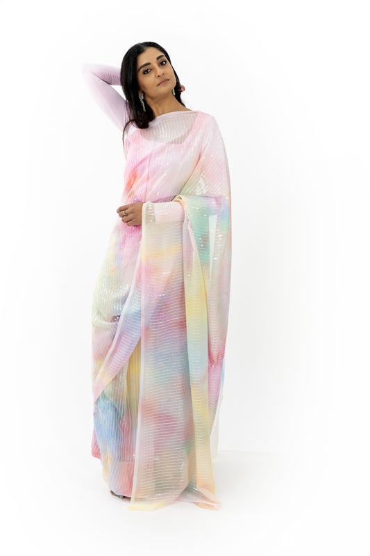 The image shows a person elegantly draped in a ready-to-wear light pink georgette saree in Australia. The saree features a radiant, iridescent quality that reflects multiple colors when light hits the fabric. The soft and flowing georgette material provides a comfortable and flattering drape. This saree is perfect for special occasions, exuding sophistication and grace.