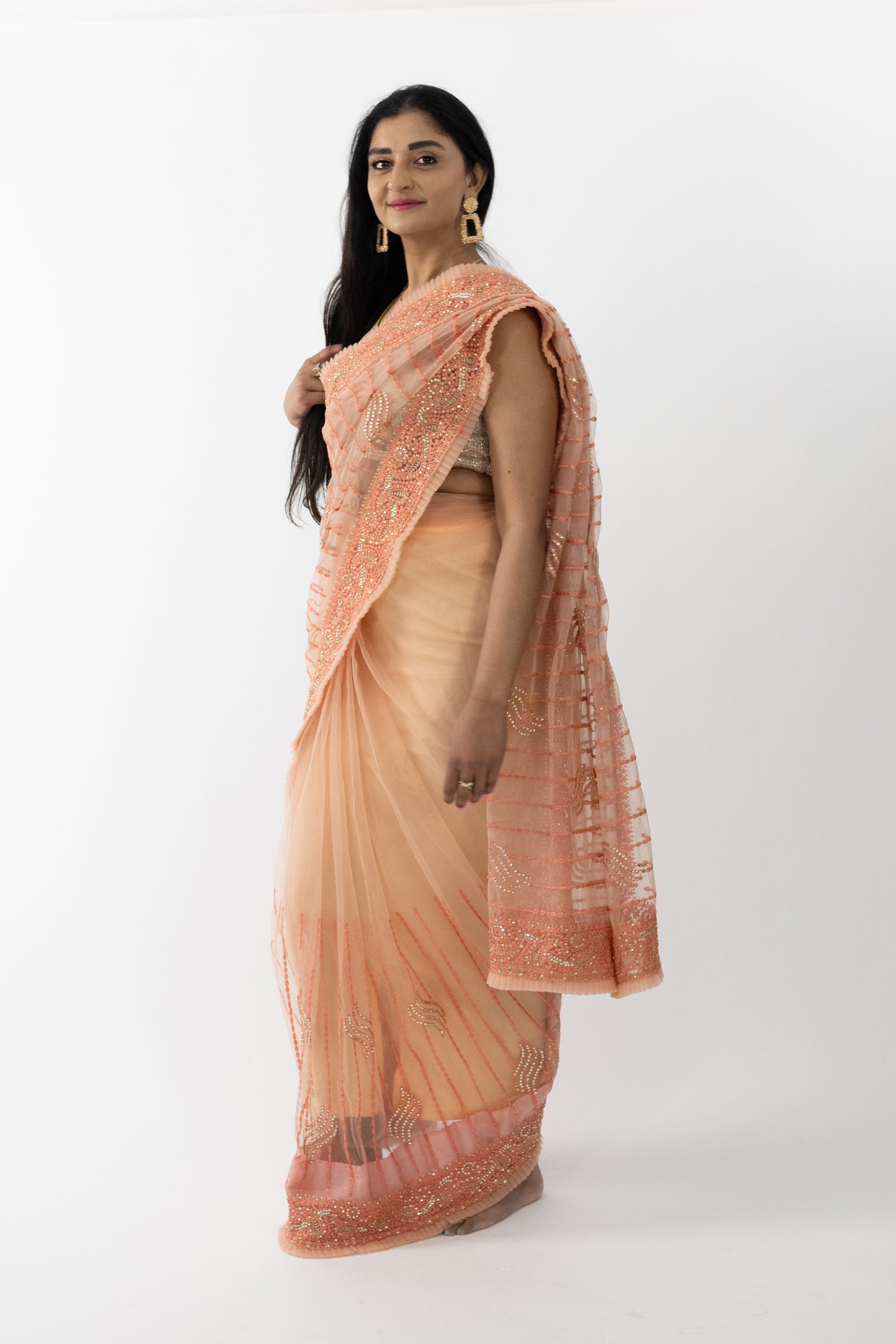 A close-up shot highlighting the exquisite ship motif detailing on the peach net saree. The intricate patterns showcase fine craftsmanship, adding a unique charm to the saree. The soft and lightweight fabric drapes beautifully, making it a stunning choice for any elegant event.